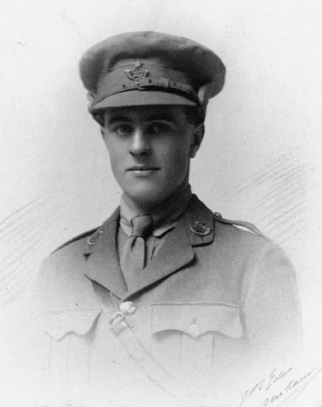 A black and white portrait of a young man in a military uniform and cap looking directly at the viewer.